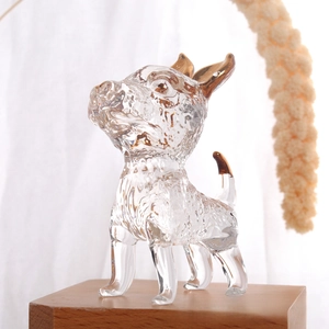 Detailed macro view of a crystal glass dog figurine with golden accents on a wooden tray