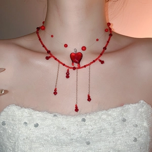 Close-up of layered red crystal heart pendant necklace with beaded tassel details