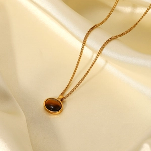 Close-up of a 18K gold-plated necklace with an oval brown tiger eye stone on silk