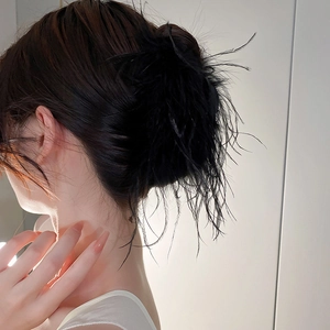 Elegant black feather hair claw clip for women shown on a stylish bun hairstyle