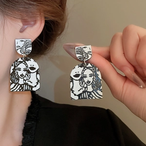 Close-up of abstract artistic earrings featuring black and white female line art illustrations