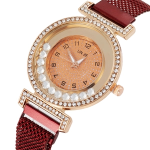 Detail of rose gold ladies watch featuring a crystal bezel and red Milanese mesh strap