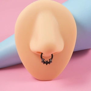 Detail of a black bat-shaped stainless steel septum ring on a silicone nose model