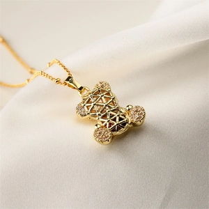 Macro shot of gold-plated hollow bear pendant with white zircon on silk background