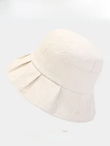 Detail view of the beige bucket hat showing its unique crinkled fabric and texture