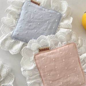 Close-up of pink and blue cotton coasters with white lace trim and dotted texture