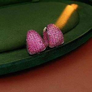 Macro detail of silver C-shaped earrings with pave-set pink zircon gemstones