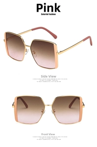 Detail view of square oversized sunglasses with gold metal frames and pink gradient lenses
