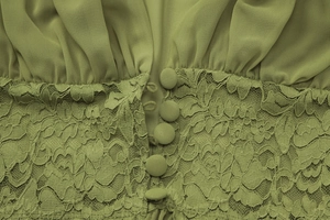 Détail chemisier vert en mousseline avec col en V, tissu plissé, dentelle et boutons en tissu