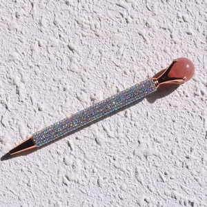Detail of colorful rhinestone ballpoint pen with rose gold trim and pink stone top