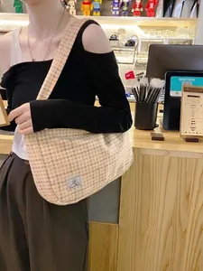 Sac à bandoulière chic à carreaux avec patch logo SR porté en situation réelle