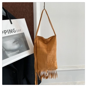 Detailed view of caramel suede crossbody bag featuring retro fringe and cross stitching