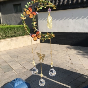 Macro shot of crescent moon wind chime with gold leaves, crystal balls and monarch butterflies