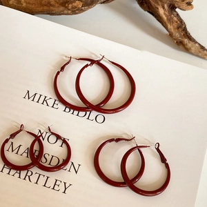 Three sizes of vintage red glossy geometric hoop earrings on artistic paper background
