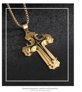 Macro view of gold cross pendant with black enamel layering and box chain detail
