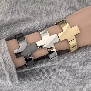 Detailed close-up of polished cross bangles in gold, silver, and black metal finishes