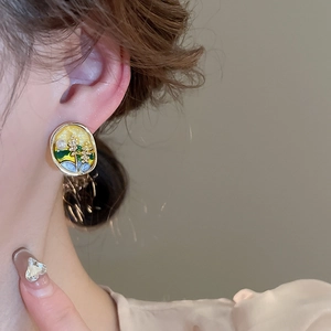 Boucles d'oreilles vintage en émail avec fleurs et cadre doré portées par un modèle