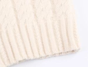 Gros plan sur la maille torsadée et l'ourlet côtelé d'un pull d'hiver crème