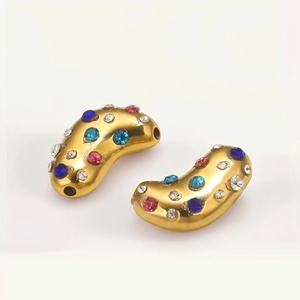 Macro shot of gold-plated bean charms with colorful rhinestones for DIY jewelry making