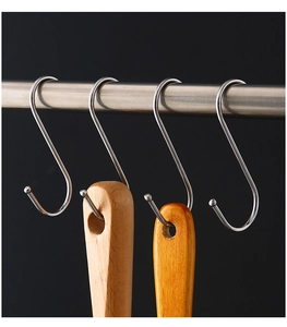 Polished S-shaped stainless steel hooks hanging kitchen utensils on a sleek metal bar