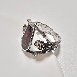 Gothic punk ring with silver skull motifs and a red coffin-shaped stone detail