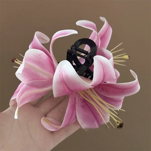 Close-up of a large pink lily hair claw clip with realistic fabric floral details