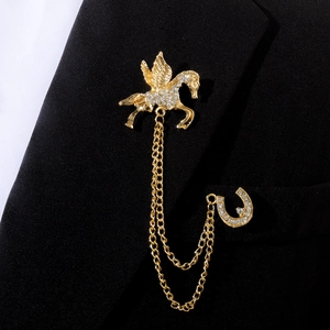 Détail de la broche pégase dorée avec fer à cheval en strass et chaînes à glands