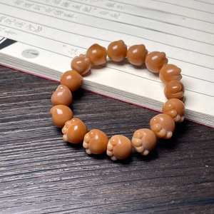 Close-up of brown pig-shaped beads on a dark wood table with Chinese calligraphy