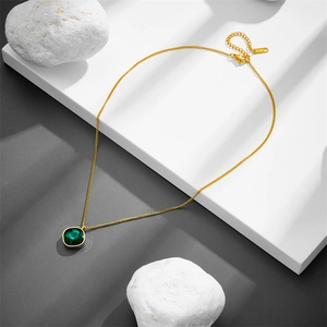 Gold geometric titanium necklace with green square zircon pendant on stone props
