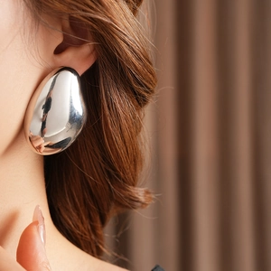 Close-up of polished silver teardrop earrings worn by a model in a fashion setting