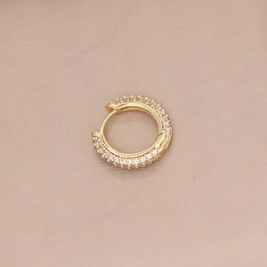 Macro detail of gold-plated hoop earring featuring micro-paved white cubic zirconia stones