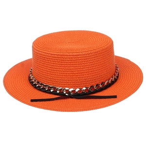 Detailed close-up of orange woven straw hat texture with black chain and ribbon trim