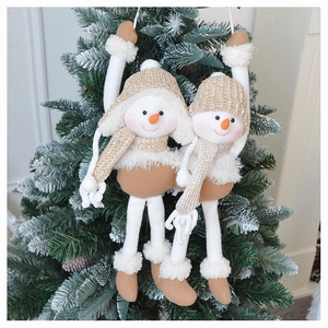 Close-up of plush snowman ornaments with knit hats hanging on a Christmas tree branch