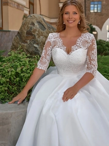 Détails du corsage en dentelle à col en V et jupe en satin d'une robe de mariée blanche