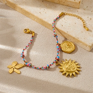 Bracelet tressé doré avec pendentifs soleil, étoile et fleur sur fond de pierre naturelle