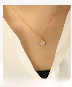 Gros plan d'un collier pendentif coeur en titane doré avec nacre blanche radiante sur modèle