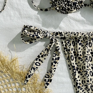 Close-up of leopard print bikini bottoms with side tie detail and beach straw decor
