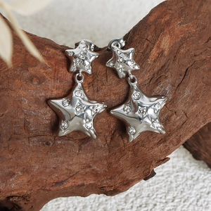 Silver star drop earrings with sparkling zircon inlay on rustic wood background