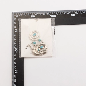 Detailed view of bohemian silver spiral earrings with blue turquoise beads and scale ruler