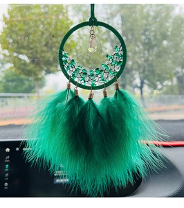 Dettaglio dell'acchiappasogni verde per auto con piume e decorazioni in pietra di cristallo
