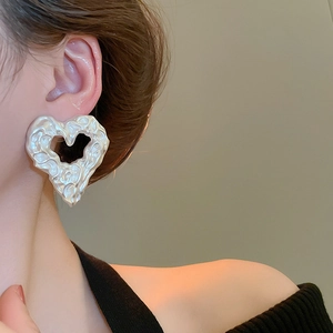 Detail of silver irregular heart earrings with lava texture on a female model