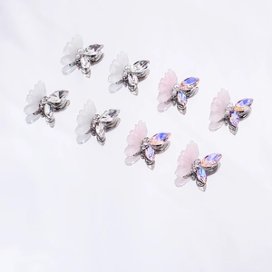 Detail view of 3D resin butterfly nail charms with rhinestones and pearls on a mirror base