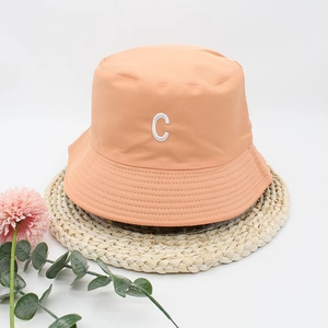 Orange cotton bucket hat with white embroidered letter C on a straw mat background