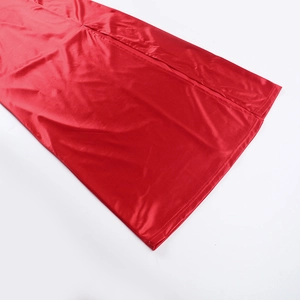 Detail of red satin dress featuring a high side slit and smooth glossy finish fabric