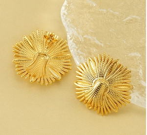 Macro view of gold flower earrings with detailed relief texture and butterfly backs