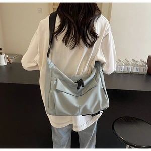 Light blue large canvas messenger bag shown on model in a cozy cafe setting