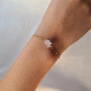 Detail of minimalist gold chain bracelet featuring an irregular pink quartz gemstone