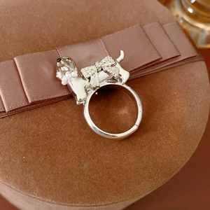 Detailed close-up of a silver dog ring with a rhinestone bow and pearl collar accent