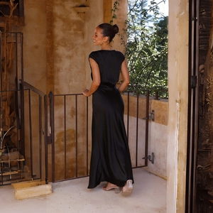 Elegant back view of black satin fishtail maxi dress on a vintage stone balcony