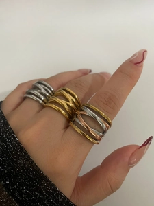 Detail of layered crisscross high-polish rings in silver, gold, and tricolor finishes